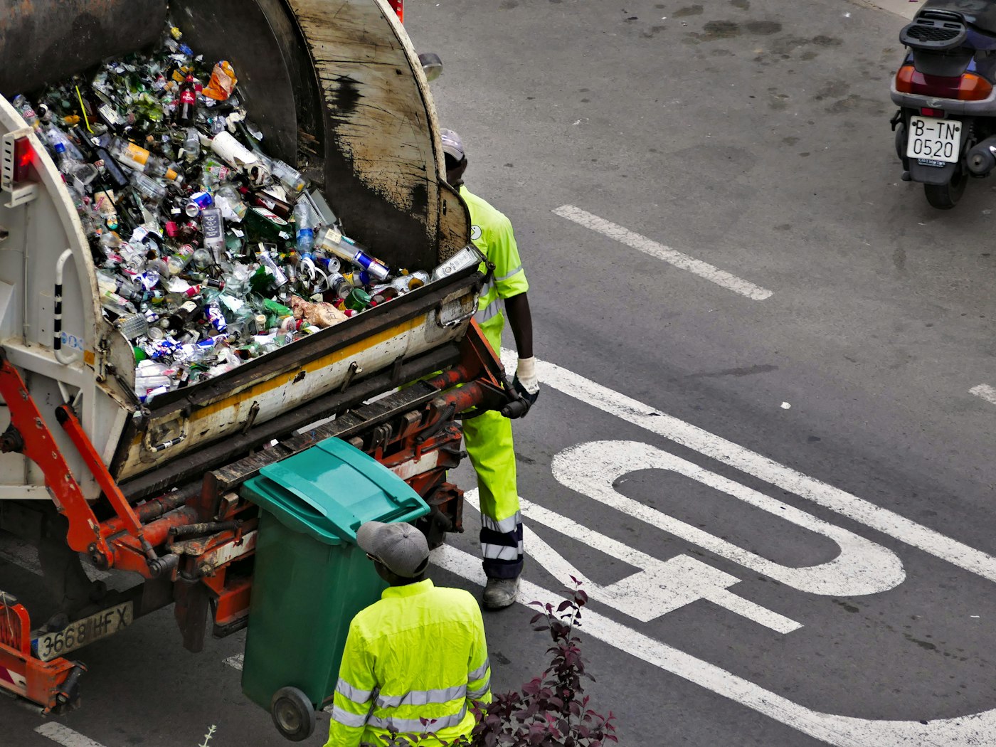 Sanitation crew loading recyclables into a packer truck on an urban route